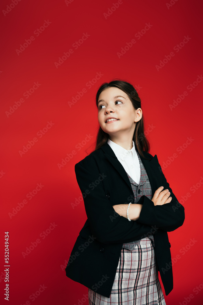 happy girl in checkered skirt and black blazer standing with crossed arms and looking back isolated on red happy girl in checkered skirt and black blazer standing with crossed arms and looking back isolated on red