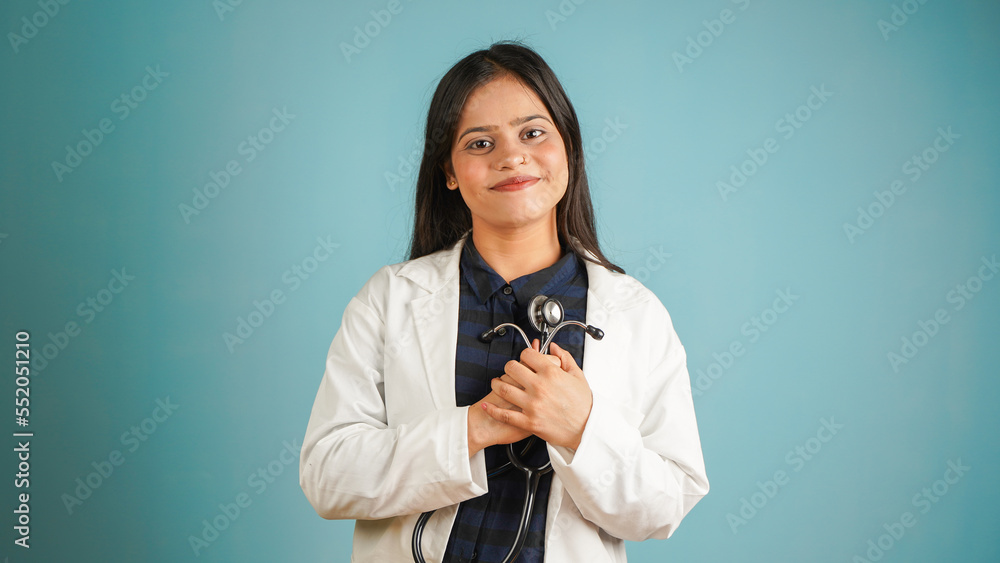 Portrait of a young female doctor holding stethoscope in her hand, Cheerful Asian Indian woman doctor in apron and stethoscope isolated blue studio background Portrait of a young female doctor holding stethoscope in her hand, Cheerful Asian Indian woman doctor in apron and stethoscope isolated blue studio background