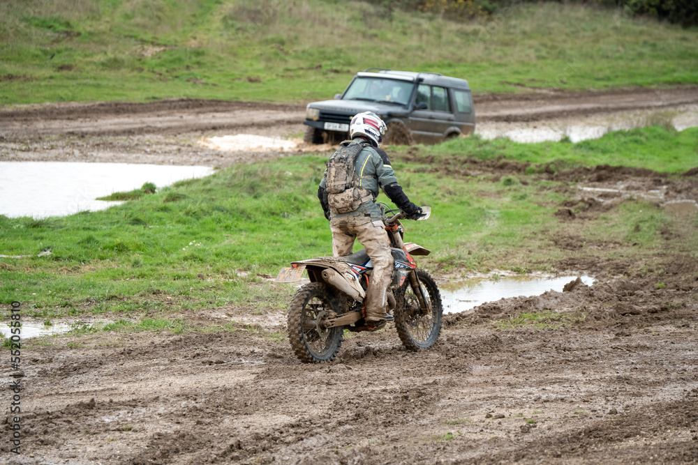 motorcyclist taking their off-road bike through muddy and very wet terrain, Wiltshire UK motorcyclist taking their off-road bike through muddy and very wet terrain, Wiltshire UK