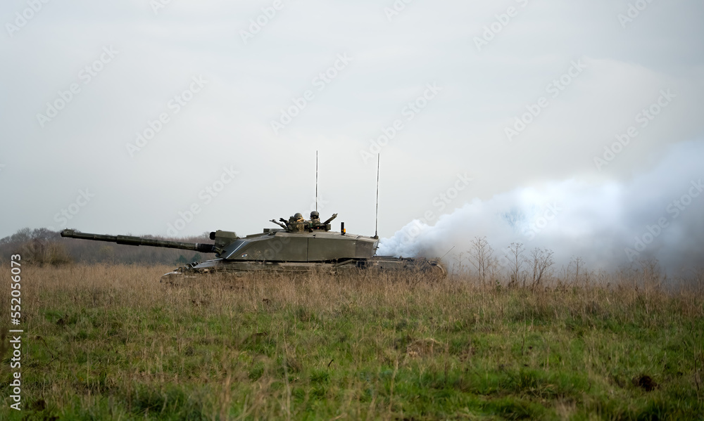 Fototapeta premium commander and gunner directing action on a British army FV4034 Challenger 2 ii main battle tank, diesel smoke screen billowing from the rear on a military exercise, Wiltshire UK