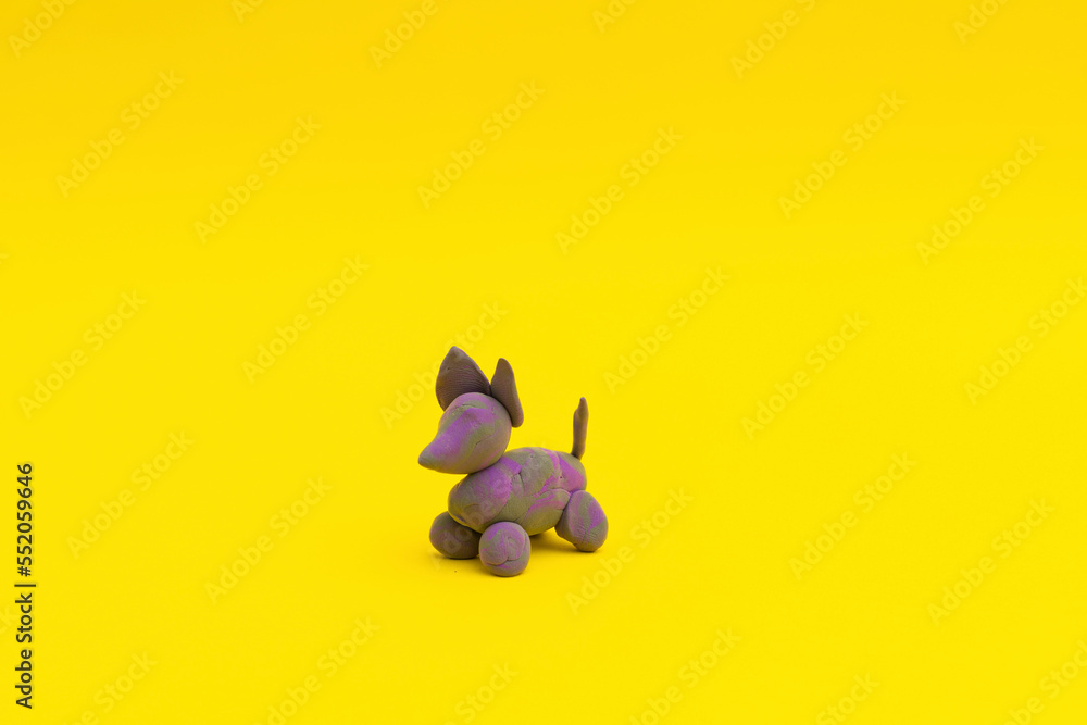 Figurine with clay looks like a dog, purple on a yellow background, children's crafts Figurine with clay looks like a dog, purple on a yellow background, children's crafts
