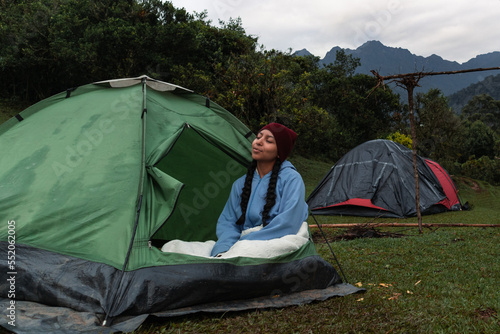 Mujer relajándose en camping con paisaje montañoso y clima frío en el Parque Nacional Farallones de Cali, Colombia.