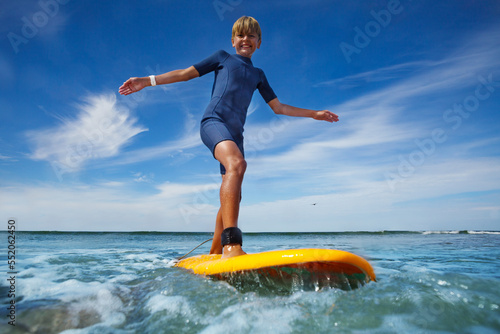 Canvas Print Boy stand on the surf board smiling balancing with hand