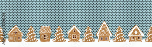 Gingerbread houses and fir trees on light blue knitted background. Gingerbread village. Seamless border. Christmas background. Fairytale winter landscape. Vector illustration