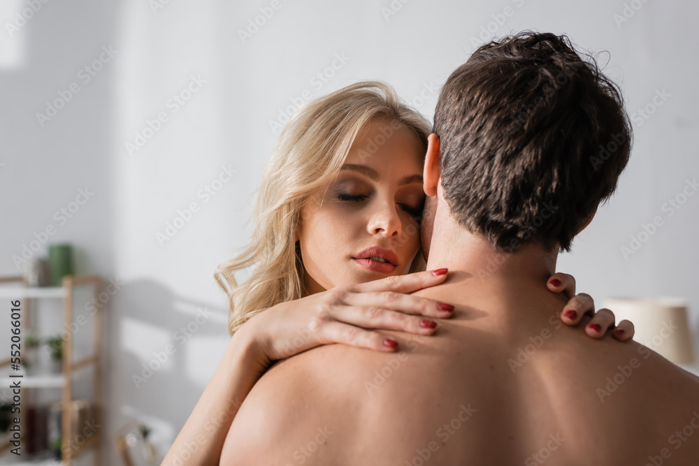 Blonde woman touching shoulders of muscular boyfriend at home. Blonde woman touching shoulders of muscular boyfriend at home.