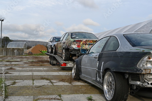 Rear view on three drift crashed cars used for drifting sport ready for transport to Grand Prix or sports car racing. Two vehicles are secured on aluminium trailer.