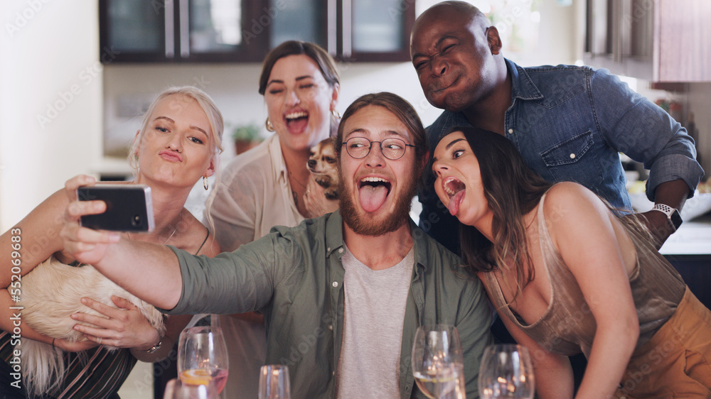 Obraz premium Friends, selfie and silly pose during dinner party at home to celebrate new years eve together. Phone, photo and funny face diverse group of people posing for a mobile picture during lunch