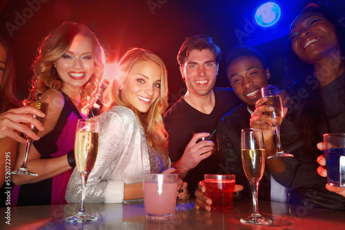 Portrait, clubbing and drinking with friends together in a nightclub for a new year celebration party. Happy, drink and cocktail with a man and woman friend group bonding in a nightclub for fun
