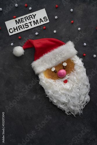 Santa's head in red hat on a dark background. May be used as card of Christmas holiday. 