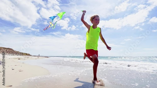 Happy boy run with colorful set of kites over sky at ocean beach