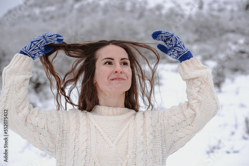 Slika na platnu A woman in a white knitted sweater and warm woollen mittens on her hands