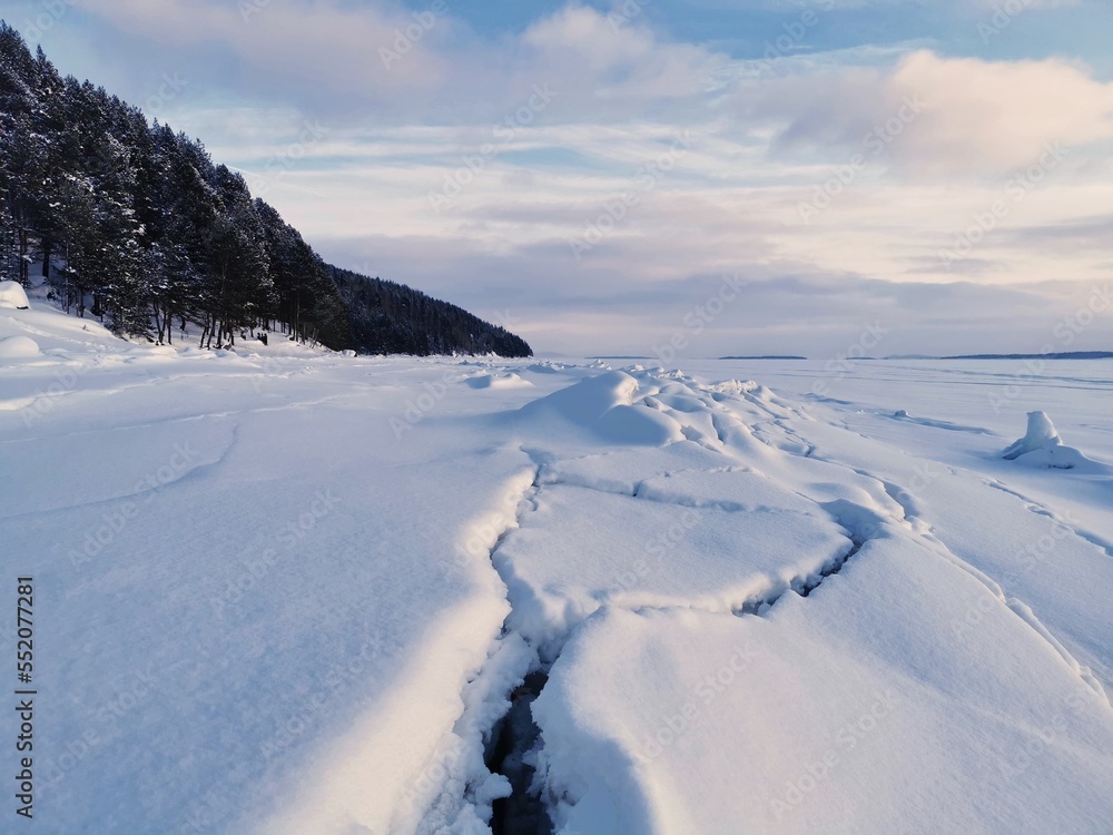 Cracks in the ice of frozen and snow-covered White sea. Kandalaksha, Kola Peninsula, Murmansk region.