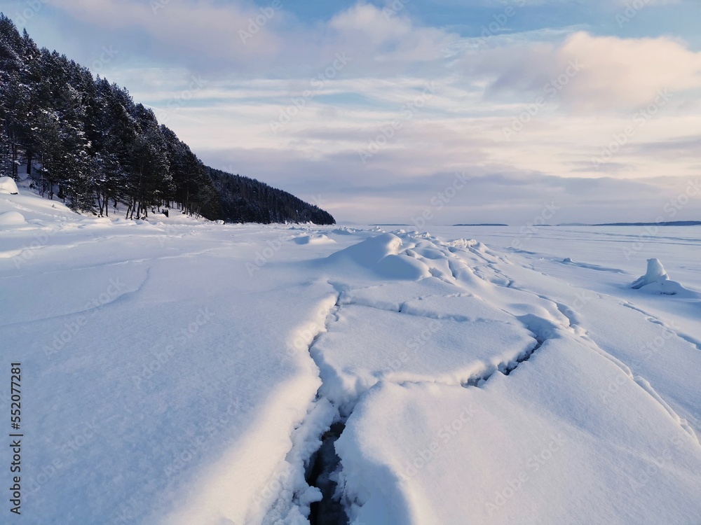 Cracks in the ice of frozen and snow-covered White sea. Kandalaksha, Kola Peninsula, Murmansk region. Cracks in the ice of frozen and snow-covered White sea. Kandalaksha, Kola Peninsula, Murmansk region.