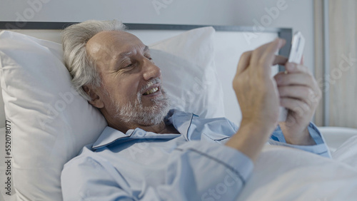 Relaxed senior man scrolling photos on smartphone, online dating app, social media