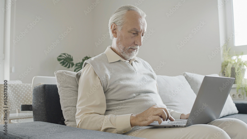 Concentrated senior man learning to use laptop at home, challenge of new technology Concentrated senior man learning to use laptop at home, challenge of new technology