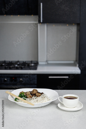 Plate with rice noodles and shiitake mushrooms. White mug with coffee