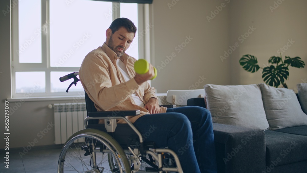 Man with disability doing dumbbell exercise while sitting in wheelchair, rehabilitation Man with disability doing dumbbell exercise while sitting in wheelchair, rehabilitation