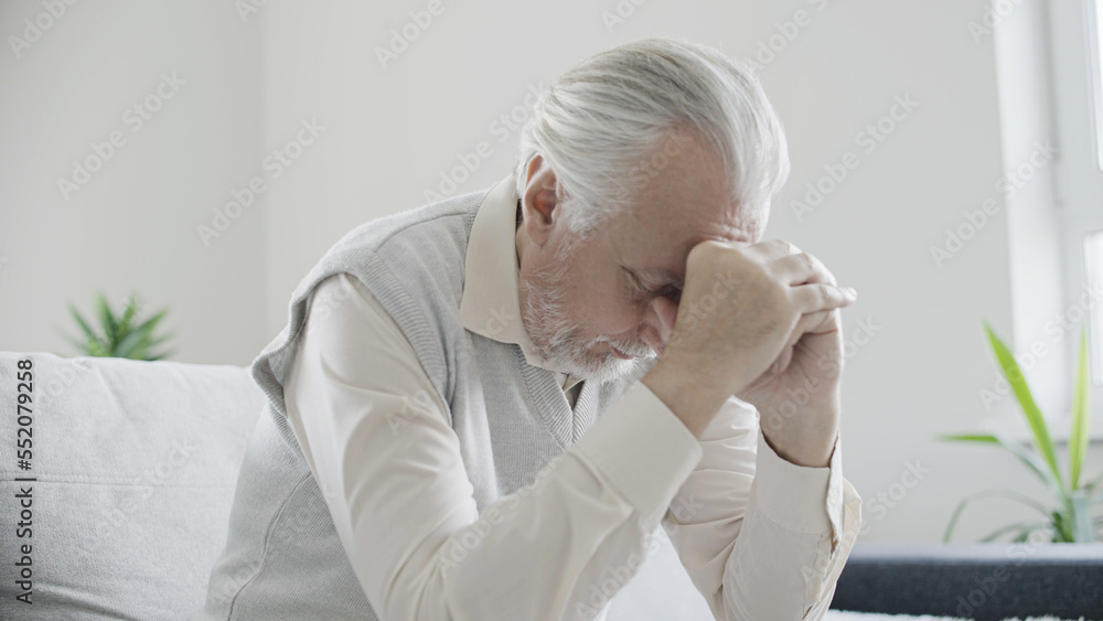 Sad old man sitting on couch alone, thinking about life, loneliness at senior age Sad old man sitting on couch alone, thinking about life, loneliness at senior age