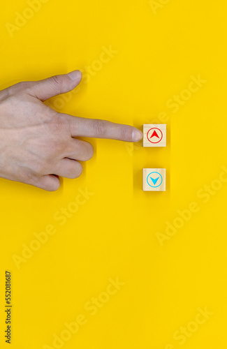 The hand that selects down among the wooden blocks marked with the up and down icon