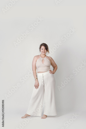 A smiling woman of large sizes in underwear. A plump girl on a light background, a positive attitude to the body.