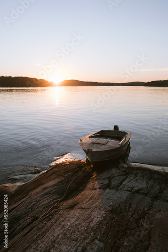 A boat at the rocky island on a lake in northern Europe at sunset