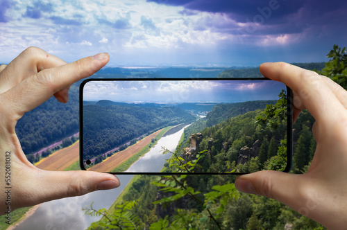 Tourist taking a picture with a mobile phone of the river Elbe at the sandstone mountains in Saxony, Germany.