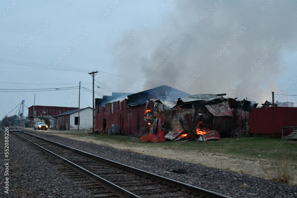 Obraz premium Train Tracks by a Burning Building