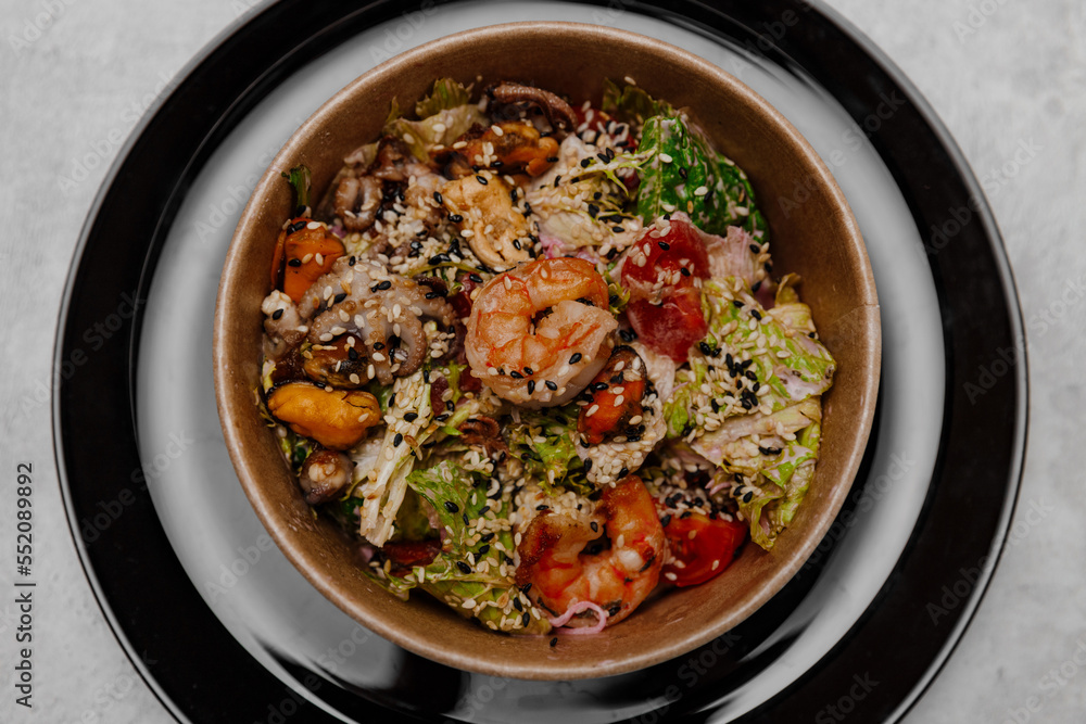 Seafood salad in a craft plate on a gray background. View from above.
Seafood salad in a craft plate on a gray background. View from above.