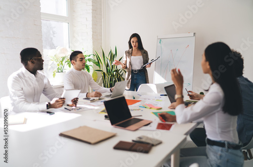 Female speaker presenting new plan to multiethnic colleagues