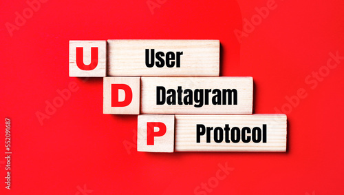 On a bright red background, wooden cubes and blocks with the text UDP User Datagram Protocol. Manufacturing of wooden toys. photo