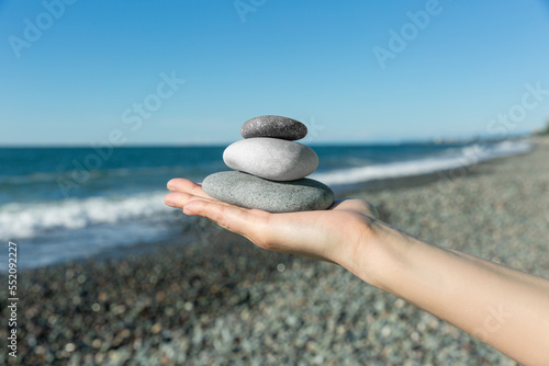 Canvas Print Balance of stones on the hand against the background of the sea
