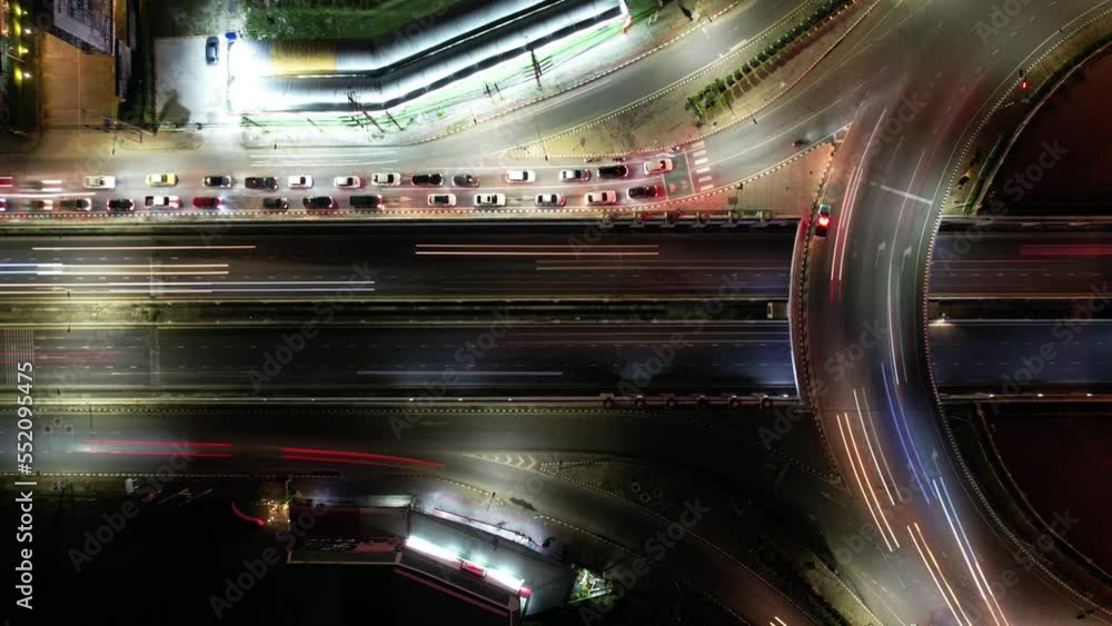 Time-lapse of car traffic transportation on road at junction intersection, 4K. Aerial view of road interchange or highway intersection with busy urban traffic speeding on the road at night, IoT GPS 5g Time-lapse of car traffic transportation on road at junction intersection, 4K. Aerial view of road interchange or highway intersection with busy urban traffic speeding on the road at night, IoT GPS 5g