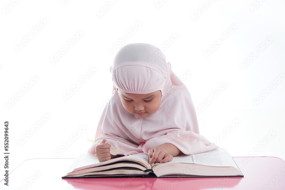 Asian Malaysian Muslim kid is reading the Quran. The Quran is indicated as the guided book for all Muslim and it is direction to be on the heaven of God.Mosque,Islam,religion and knowledge concept.