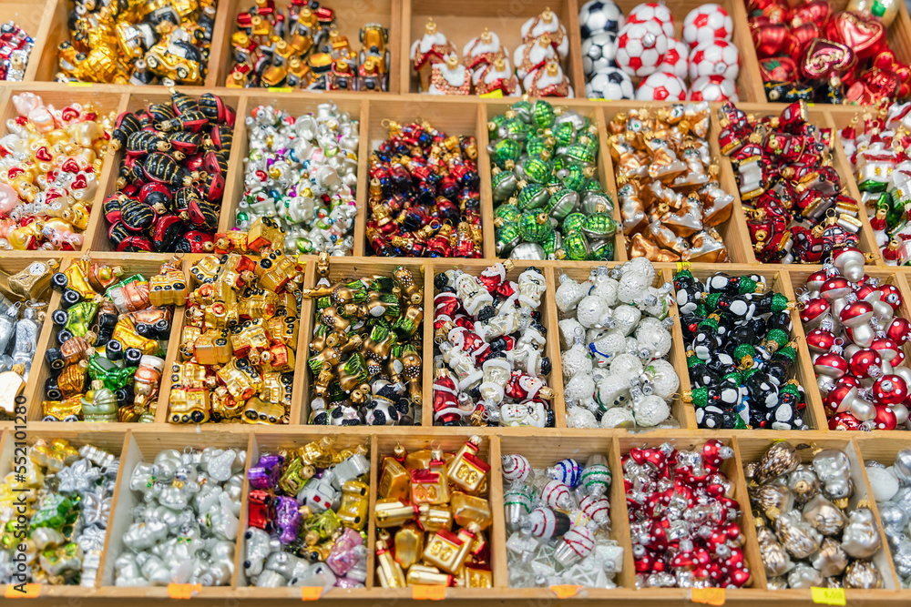 Fototapeta premium Glass toys for the festive decoration of the Christmas tree on the counter of the street bazaar on the eve of Christmas and New Year. Sales and purchases of toy decorations in December