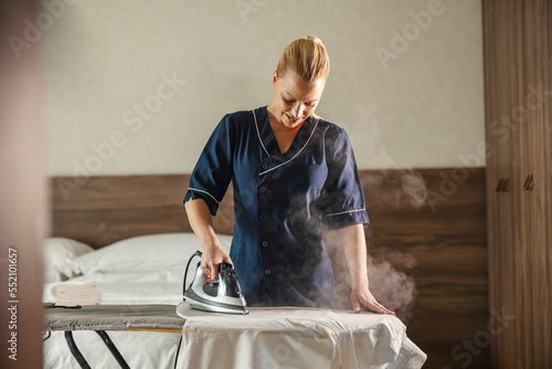 Wall Mural A maid is ironing shirt in a hotel room.