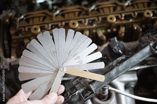 auto mechanic Using Feeler gauge Set the car valve. Measuring valve clearance with tappet feeler gauge set
