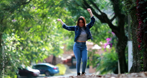 Young woman celebrating success enjoying life dancing outside in street