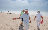 anziani amici camminano tutti insieme in spiaggia al mare