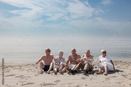 Un gruppo di anziani si diverte seduti nella spiaggia in riva al mare   photo