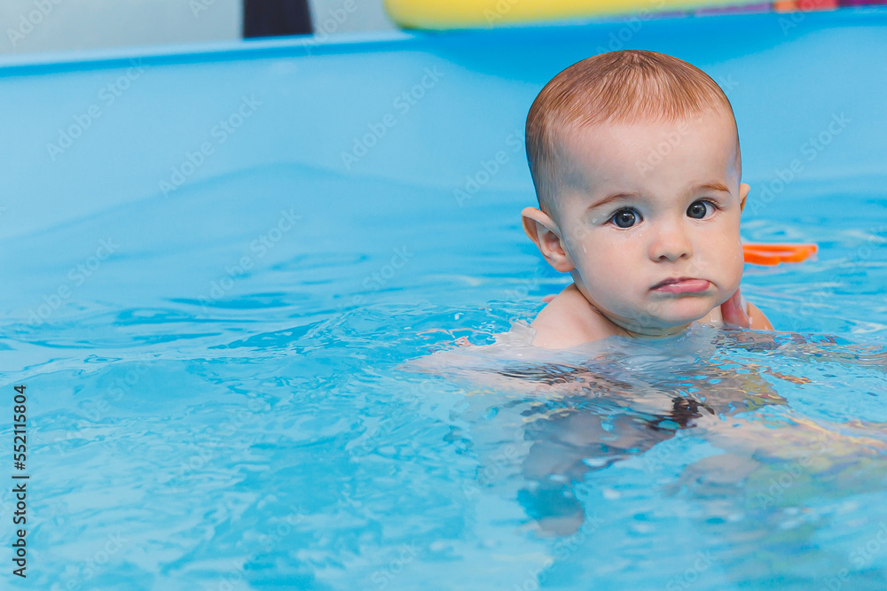 A little boy is learning to swim in a baby pool. Children's development. First swimming lessons for children
