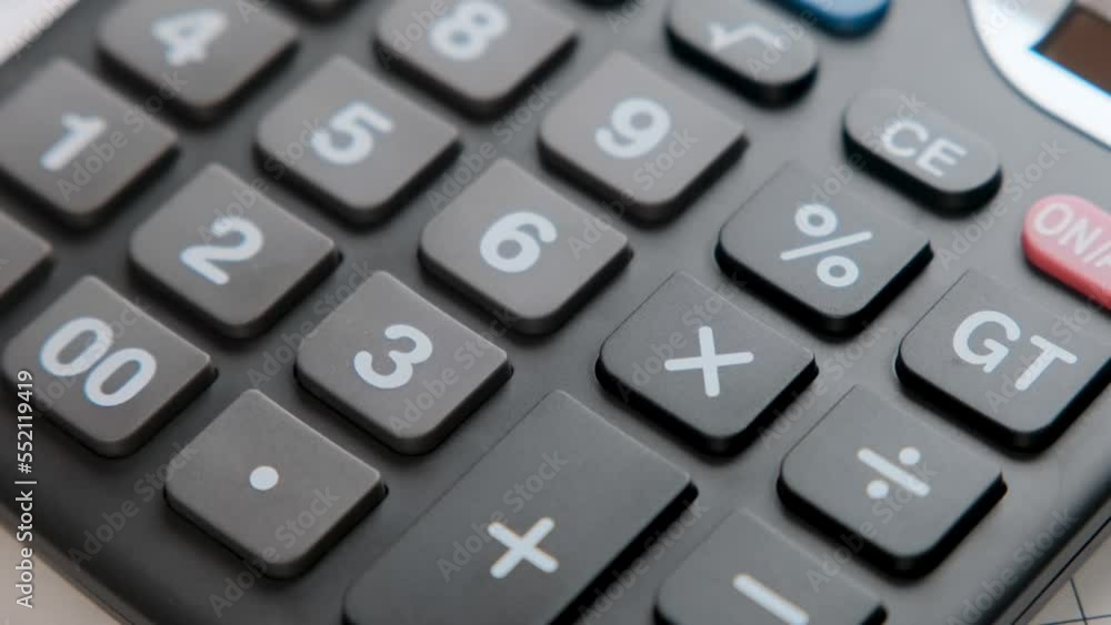 Close-up of a woman's hand counting household expenses on a calculator related to monthly bank payments. Close-up of a woman's hand counting household expenses on a calculator related to monthly bank payments.