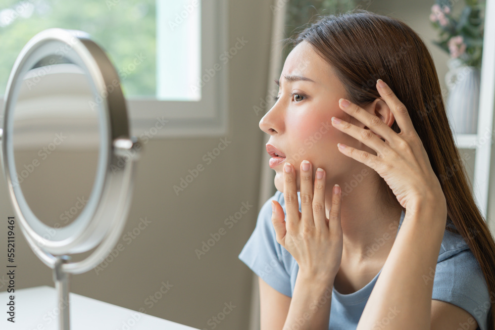 Dermatology, scratch asian young woman looking at mirror, expression worry and itch, itchy allergy or allergic sensitive reaction, red spot or rash on her face. Beauty care from skin problem treatment Dermatology, scratch asian young woman looking at mirror, expression worry and itch, itchy allergy or allergic sensitive reaction, red spot or rash on her face. Beauty care from skin problem treatment