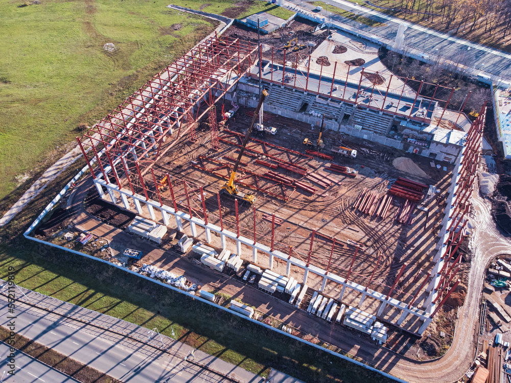 Aerial shot of construction site with metal frame and truck cranes.
