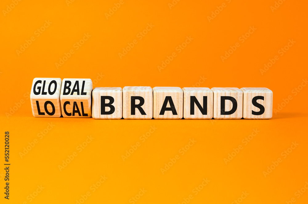 Global or local brands symbol. Concept words Global brands and Local brands on wooden cubes. Beautiful orange table orange background. Business global or local brand concept. Copy space. Global or local brands symbol. Concept words Global brands and Local brands on wooden cubes. Beautiful orange table orange background. Business global or local brand concept. Copy space.