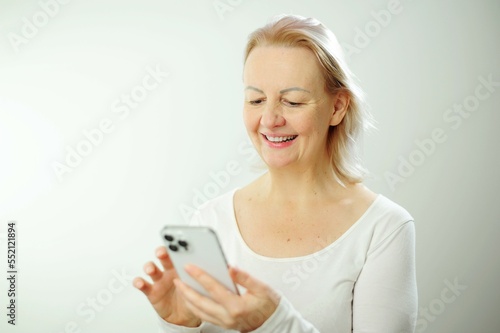 Cheerful happy adult beautiful girl looking at camera smiling laughing over white background Beautiful candid woman with short hair and without makeup Mobile phone in hand