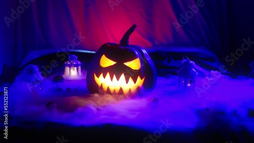 Halloween pumpkin with glowing eyes and a malicious smile releasing smoke