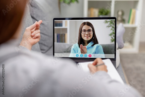 Videochat between two women, friends ladies have video call at leisure time, light living room interior, connection people concept