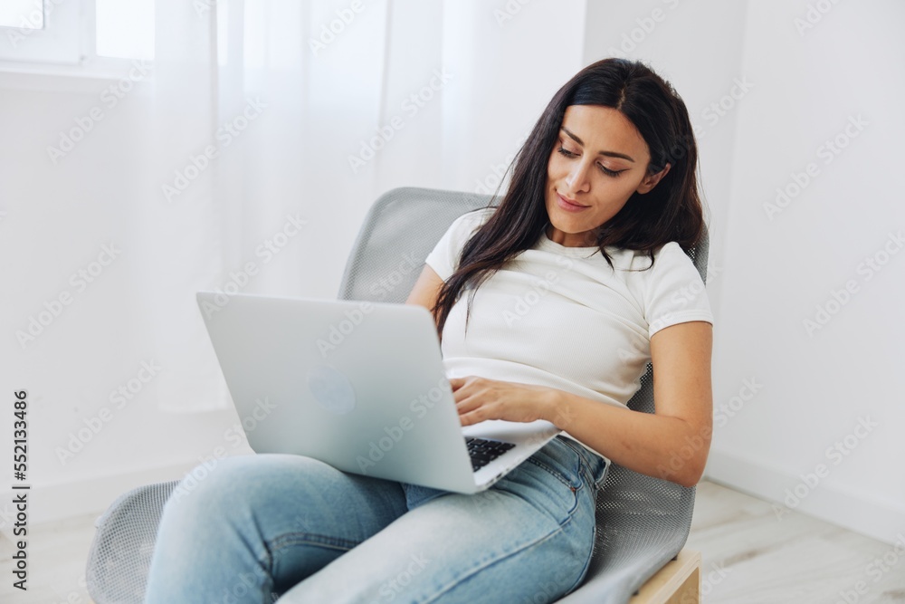 Woman ordering things online via website at online store via laptop at home sitting in chair, technology in business, shopping online Woman ordering things online via website at online store via laptop at home sitting in chair, technology in business, shopping online