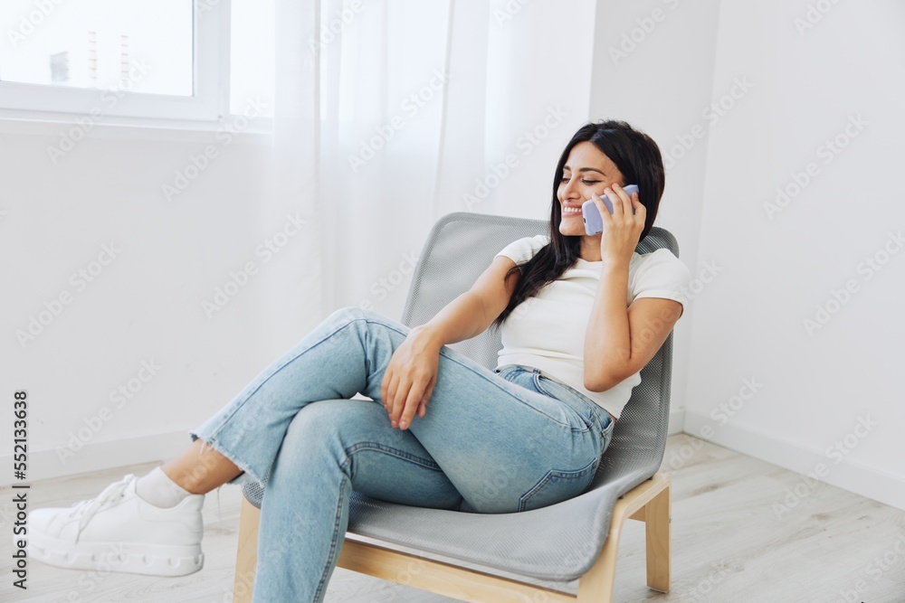 A woman talking on the phone at home sitting in a chair and smiling with her teeth, online communication as a lifestyle A woman talking on the phone at home sitting in a chair and smiling with her teeth, online communication as a lifestyle