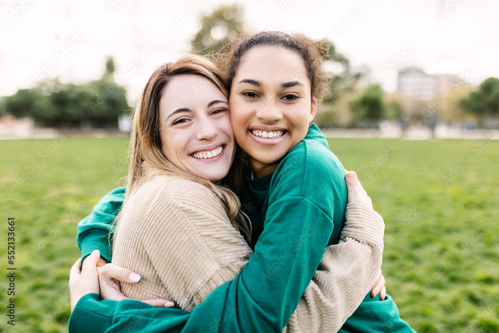 Portrait of happy young multi-ethnic female best friends hugging each other in the park Portrait of happy young multi-ethnic female best friends hugging each other in the park